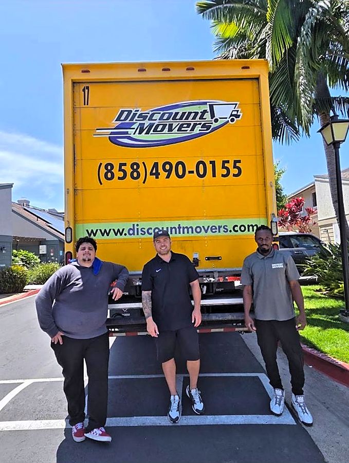 Three Discount Movers crew members standing at the rear of a company truck in San Diego
