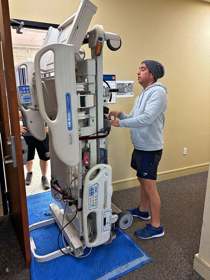 Discount Movers crew member moving a Hill-Rom hospital bed on protective blankets through a facility doorway