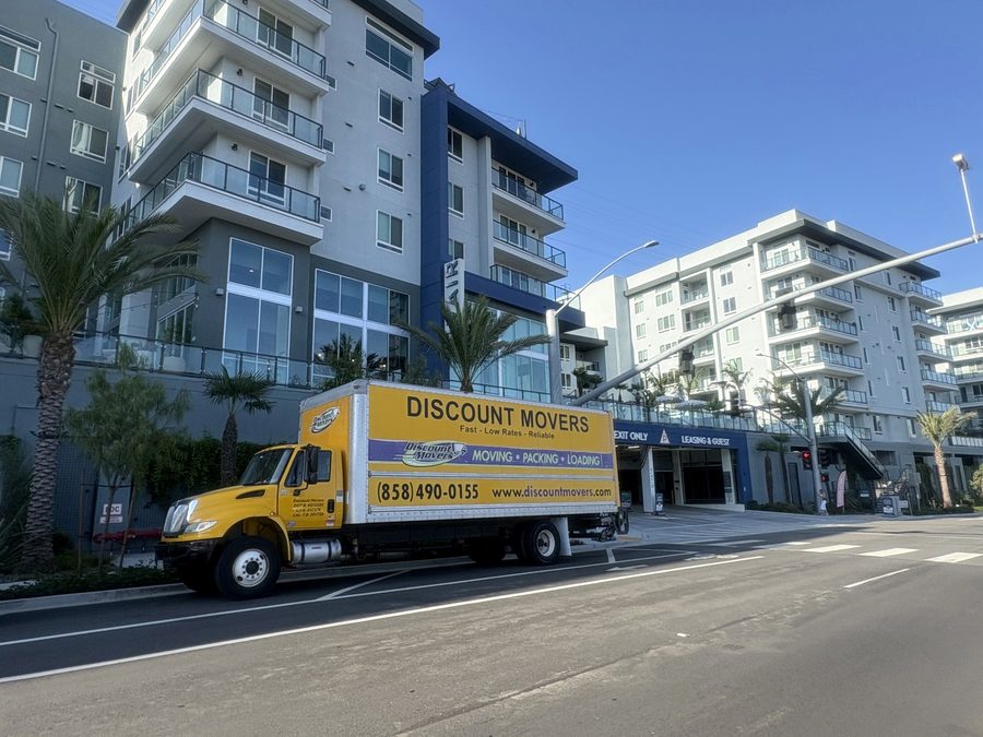 Discount Movers truck at the curb outside a mid-rise apartment complex in Mission Valley, San Diego, beside the garage entrance