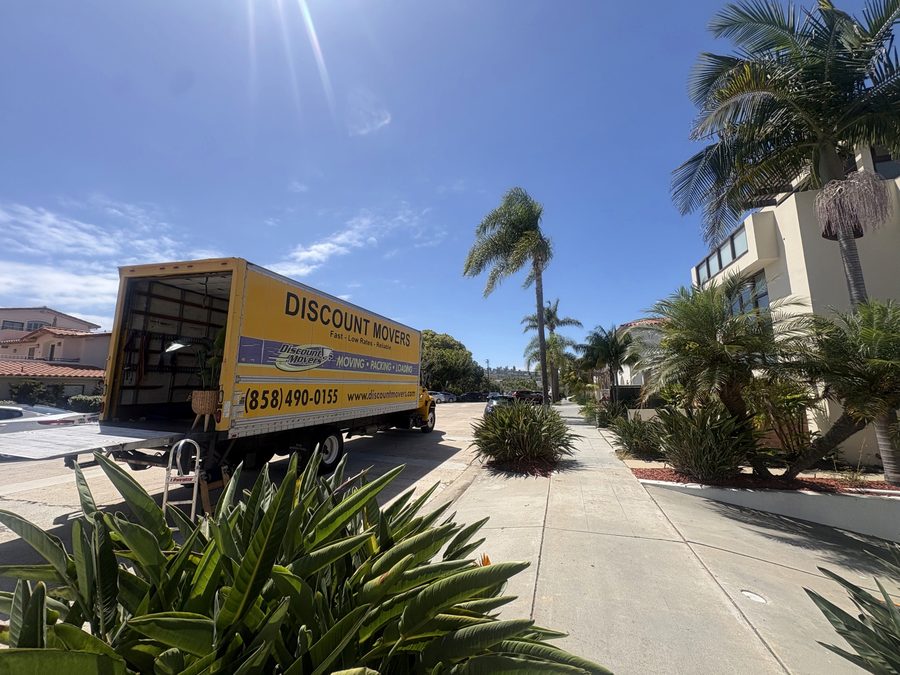Discount Movers truck at the curb on a palm-lined Point Loma street, liftgate down with a dolly ready