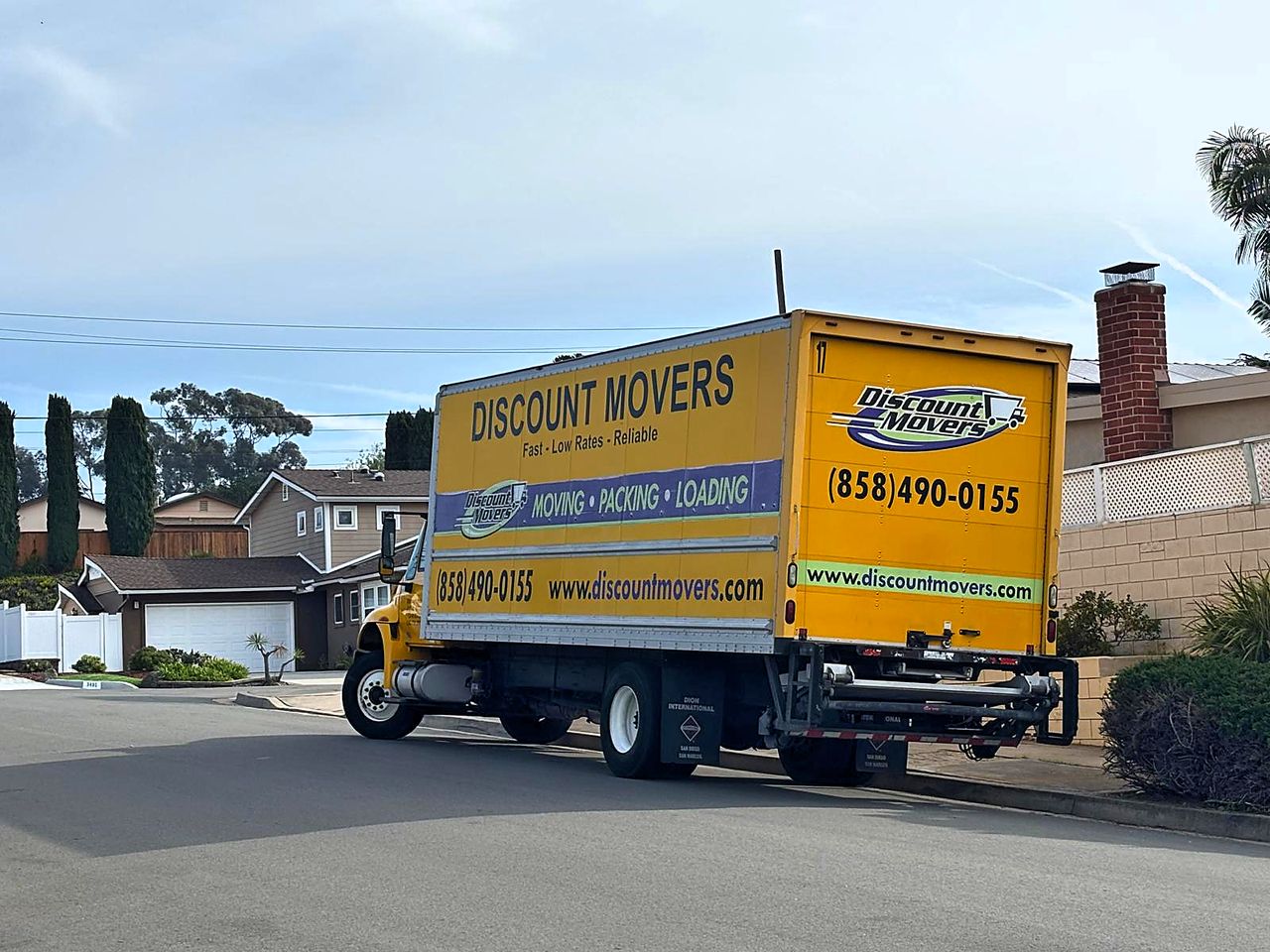 Discount Movers yellow box truck parked on a San Diego residential street, phone number and website visible on the side